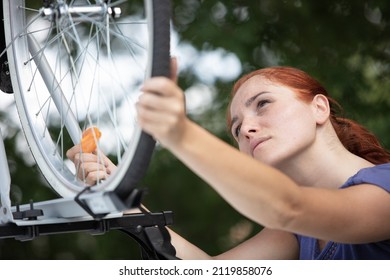 Female Cyclist Putting Mountain Bike From Rack On Car