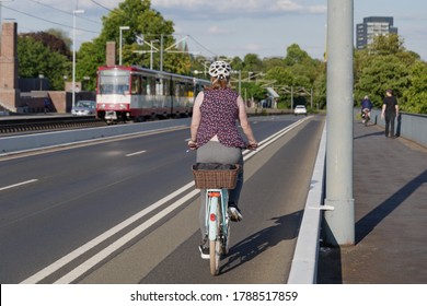 Female Cyclist Ride Bicycle On Bicycle Lane Beside Road On The Bridge Cross Rhine River In Düsseldorf, Germany. Cycling Friendly City Concept In Europe. 