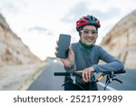 female cyclist riding bike and holding blank screen phone with blurred background