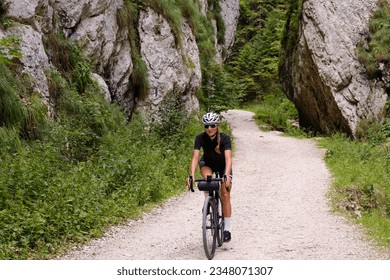 Female cyclist riding a gravel bike through rocky mountain terrain. Gravel biking adventure on beautiful mountain trails. Outdoor sport activity.Fit pretty cyclist training on nature. - Powered by Shutterstock