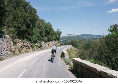 Female Cyclist Riding Through Mountain Road Forest