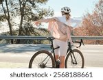 Female cyclist takes off her jacket after a ride, enjoying the scenic view. Active lifestyle, healthy living, and outdoor adventures.