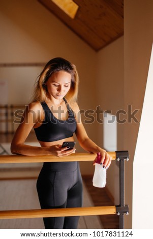 female dancer using phone by mirror in studio