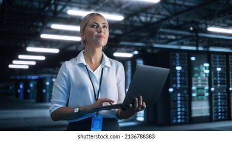 Female Data Center IT Technician Standing at the Server Rack Corridor with Laptop Computer. She is Visually Inspecting Something while Looking at the Screen. Night Office Concept - Powered by Shutterstock