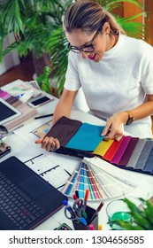 Female Decorator Looking At Fabric Samples In Her Office