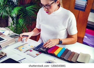 Female Decorator Looking At Fabric Samples In Her Office