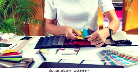 Female Decorator Looking At Fabric Samples In Her Office