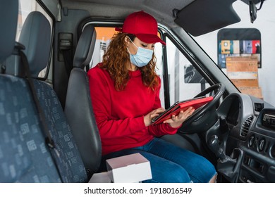 A Female Delivery Driver With A Medical Mask Tracking A Package On Her Tablet