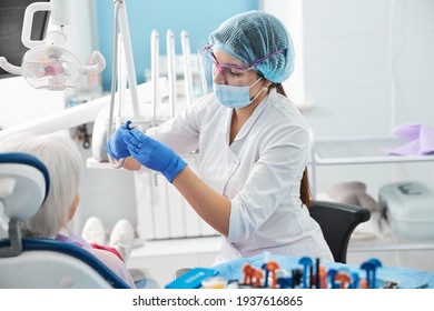 Female dental surgeon inserting a bur in handpiece