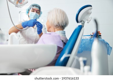 Female Dentist Assembling A Dental Drill Before Aged Woman