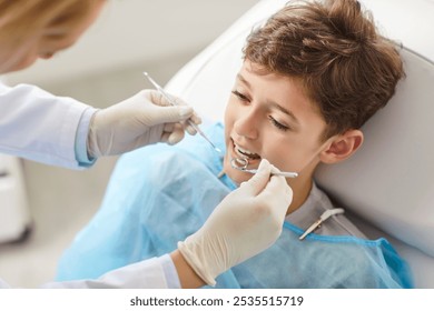 Female dentist in clinic treating childs teeth, close-up. Dental checkup of boy, caries treatment. Concept child dental checkup, dental hygiene, health care and medicine, dental hygiene - Powered by Shutterstock