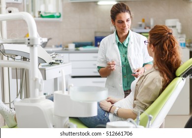 Female Dentist In Dental Office Talking With Female Patient And Preparing For Treatment.