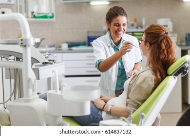 Female dentist in dental office talking with female patient and preparing for treatment.
