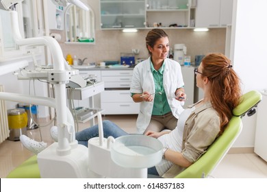 Female Dentist In Dental Office Talking With Female Patient And Preparing For Treatment.