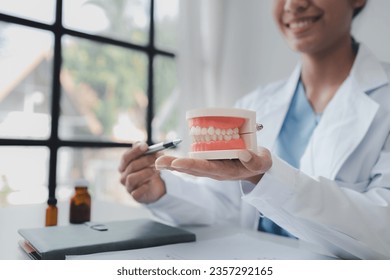 Female dentist with dentures for explaining teeth, recommending orthodontic guidelines, dentist consulting patient's symptoms and endodontic treatment. Dental treatment concept.
