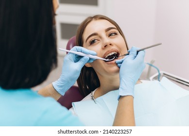 Female Dentist Examines Her Patient In A Dental Chair.