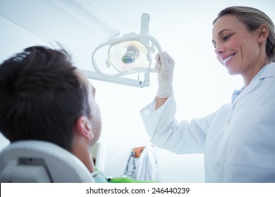 Female dentist examining mans teeth in the dentists chair - Powered by Shutterstock