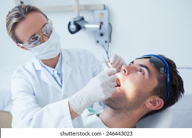 Female Dentist Examining Mans Teeth In The Dentists Chair