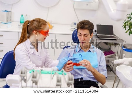Female dentist giving goggles to male patient