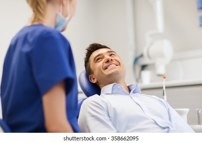 Female Dentist With Happy Male Patient At Clinic