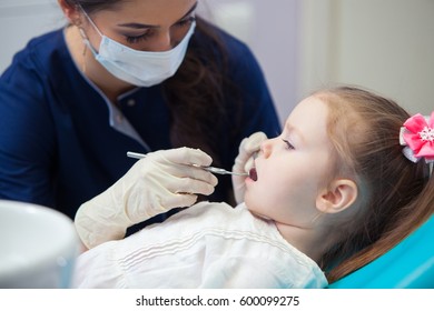 Female Dentist In Mask Treats Teeth Little Girl