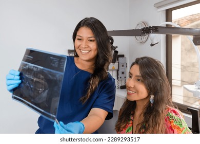 Female dentist and Patient discussing Panoramic X-Ray Results in her dental office - Powered by Shutterstock