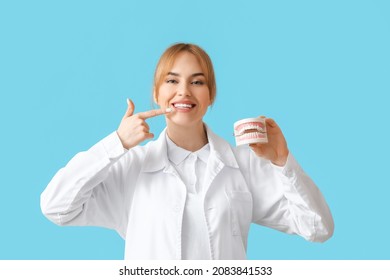 Female Dentist With Plastic Jaw Model On Color Background