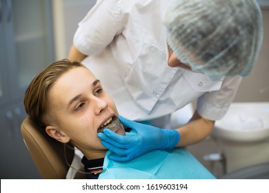 Female Dentist Puts On A Guy Patient A Mouth Guard In Dental Office.