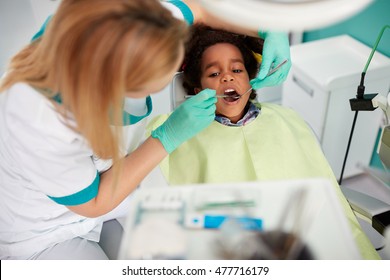Female dentist repair tooth to nice black kid in dental practice