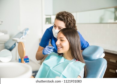 Female dentist showing braces to teenage girl in mirror at dental clinic - Powered by Shutterstock