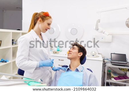 Female dentist supporting male patient