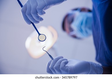 Female Dentist In Surgical Mask Holding Dental Tools In Dental Clinic