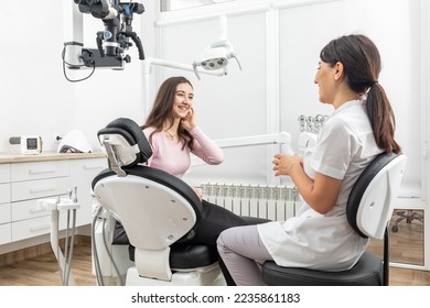 Female dentist talking to a young patient during appointment in modern dental clinic before teeth treatment - Powered by Shutterstock