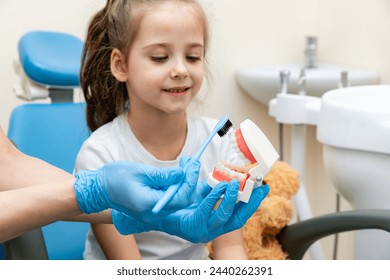 Female dentist teaches a little girl how to brush her teeth properly with jaw model and toothbrush. The concept of oral care. concept of dentistry. children's dentist. plasma structure of the jaw - Powered by Shutterstock