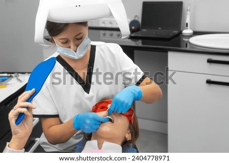 Female dentist teaches a female patient how to properly brush her teeth with dental floss. Professional dental flossing in the dental office. Dental and oral health