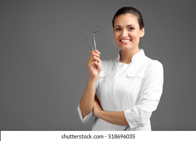 Female Dentist With Tools On Grey Background