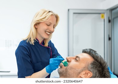 Female dentist treating teeth to patient, mid age man in chair at dental clinic. Dentistry, healthy teeth, medicine and healthcare concept - Powered by Shutterstock