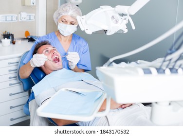 Female Dentist Treating Young Male Patient In Dental Office