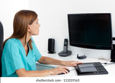 Female dentist using computer at office desk