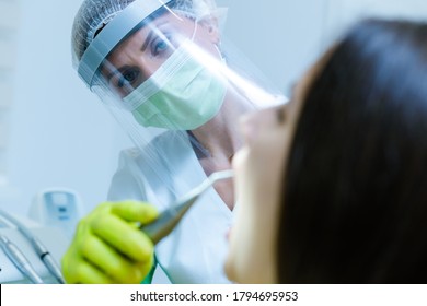 Female Dentist Wearing  Face Mask, Gloves And Visor As Coronavirus Safety Precaution Checkup Dental Health Of Young Woman