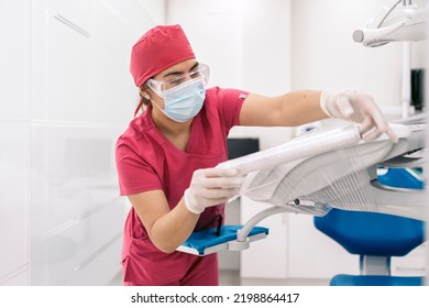 Female Dentist Working In Modern Dental Clinic And Wearing Face Mask. She Is Also Wearing Dental Safety Glasses.