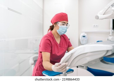 Female Dentist Working In Modern Dental Clinic And Wearing Face Mask. She Is Also Wearing Dental Safety Glasses.