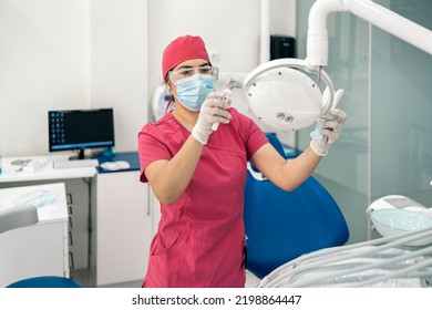 Female Dentist Working In Modern Dental Clinic And Wearing Face Mask. She Is Also Wearing Dental Safety Glasses.