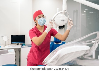 Female Dentist Working In Modern Dental Clinic And Wearing Face Mask. She Is Also Wearing Dental Safety Glasses.