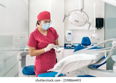 Female Dentist Working In Modern Dental Clinic And Wearing Face Mask. She Is Also Wearing Dental Safety Glasses.