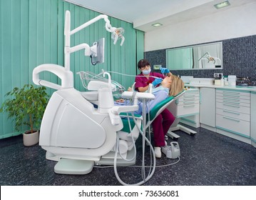 Female Dentist Working On Patient In Modern Dental Surgery