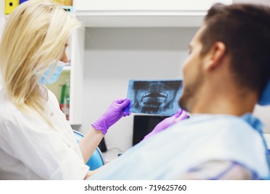 Female dentist and young man patient in dentist office. - Shutterstock ID 719625760