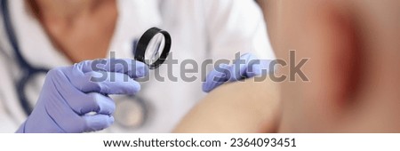 Female dermatologist examining patient skin with magnifying glass at consultation in hospital. Dermatology and skin diseases concept.