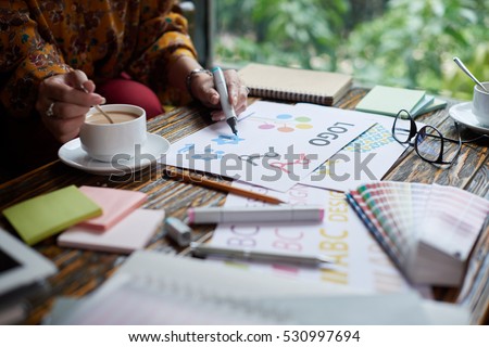 Female designer drinking coffee and working on logo