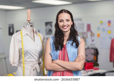 Female designer standing in fashion studio by wrap dress on mannequin with yellow measuring tape. Creative, craftsmanship, workspace, atelier, couture, inspiration, trendsetting